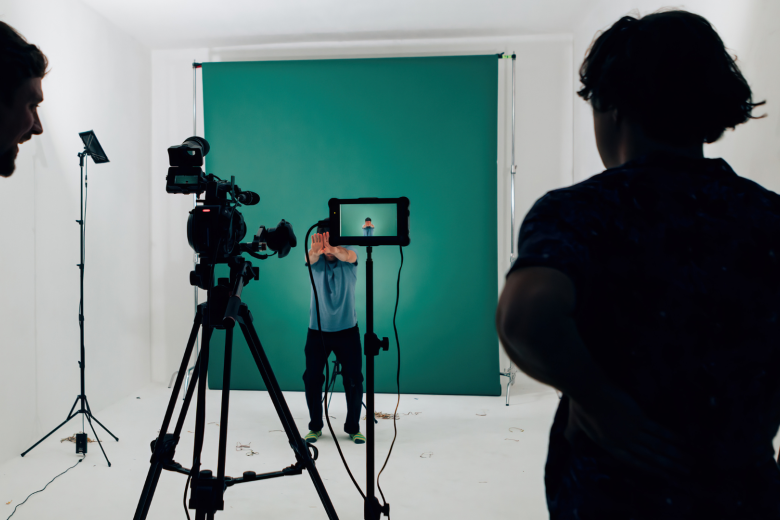 man standing in front of a camera in a green room